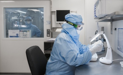 Une opératrice en équipement pour salle blanche analyse un composant pour vérifier sa qualité