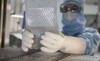 Un opérateur en équipement pour salle blanche démoule un plaque de piston après vulcanisation dans les presses